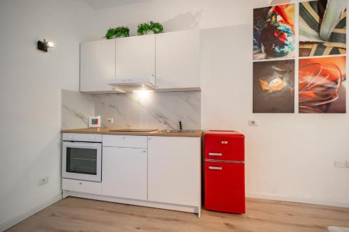 a kitchen with white cabinets and a red refrigerator at Renzo & Lucia Living Lake in Malgrate
