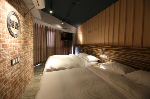 a hotel room with two beds and a clock on the wall at R10 Eco Hotel in Kaohsiung