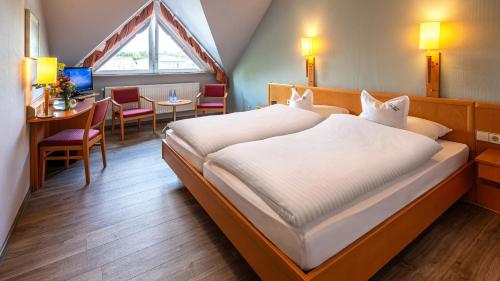 a bedroom with a large bed and a table at Hotel Restaurant "Zur Post" in Holdorf