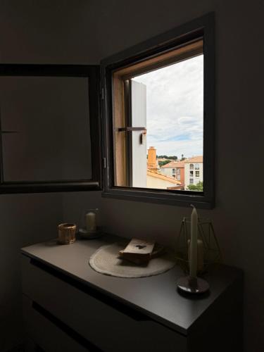 une salle de bain avec une fenêtre et une table avec une bougie dans l'établissement Location à la semaine bel appartement Cap D agde, au Cap d'Agde