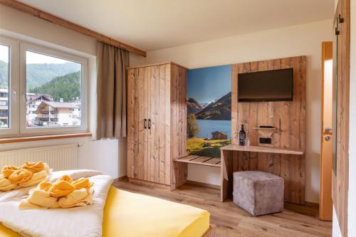 Habitación de hotel con ventana grande y TV en Appartementhaus Arbiskogelblick, en Gerlos
