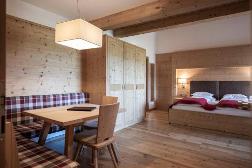 a room with a table and a bed in the background at Dolomites Nature Hotel Vigilerhof in Siusi