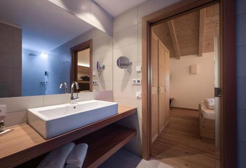 a bathroom with a white sink and a toilet at Dolomites Nature Hotel Vigilerhof in Siusi