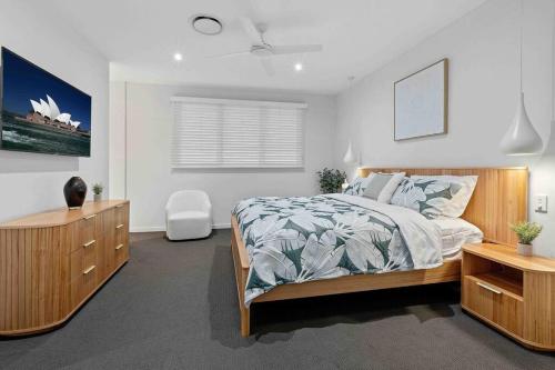 a bedroom with a bed and a dresser and a window at Redcliffe CBD Family Beach House in Redcliffe