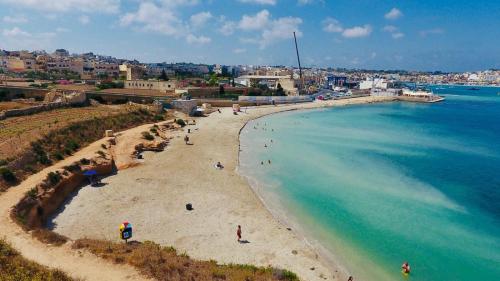 a group of people on a beach near the water at Sea & Sky townhouses in Marsaxlokk