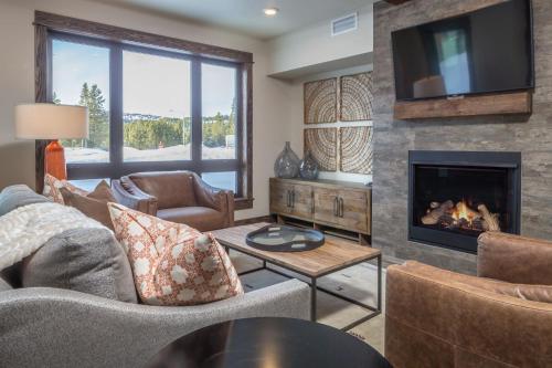 a living room with a fireplace and a tv at Mountain Lake Condo | Unit 102B in Big Sky