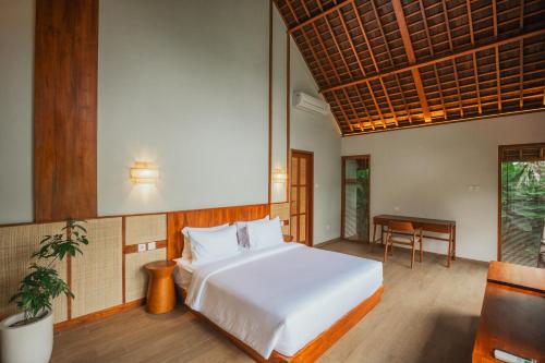 a bedroom with a white bed and a table at Arpana Luxury Private Pool Villas in Jimbaran