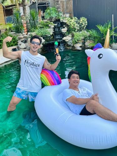 two men in the water on an inflatablevisor in a pool at Cóc Retreat Mỹ Tho City in My Tho