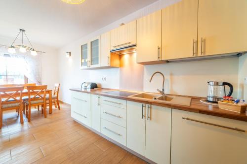 a kitchen with white cabinets and a dining room at Promenada Apartamenty i Domek Nad Jeziorem in Mikołajki