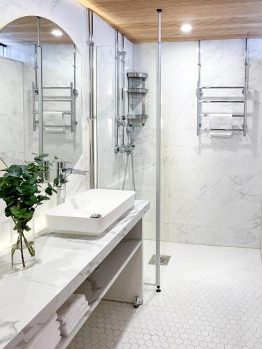 a white bathroom with a sink and a shower at Gustavelund Apartments in Tuusula