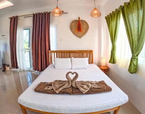 a bedroom with a bed with two heart shaped towels on it at Divers Lodge Plumeria in Moalboal