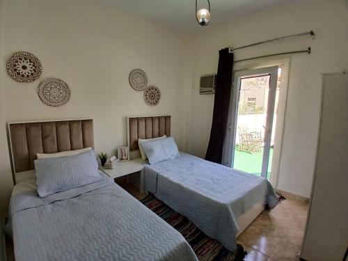 a bedroom with two beds and a door to a yard at Villa in a compound with a rooftop in sheikh zayed in Sheikh Zayed