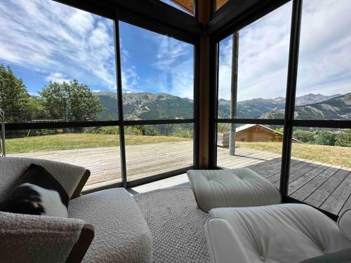 a living room with a couch and a large window at Chalet d'architecte avec vue panoramique in Allos