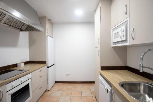 a kitchen with white cabinets and a sink at Hotel Rural Valleoscuru in Tresgrandas