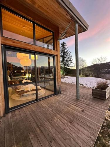 a house with a large glass window on a wooden deck at Chalet d'architecte avec vue panoramique in Allos