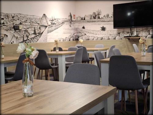 a restaurant with tables and chairs with a mural on the wall at Hotel Unicornis in Eger