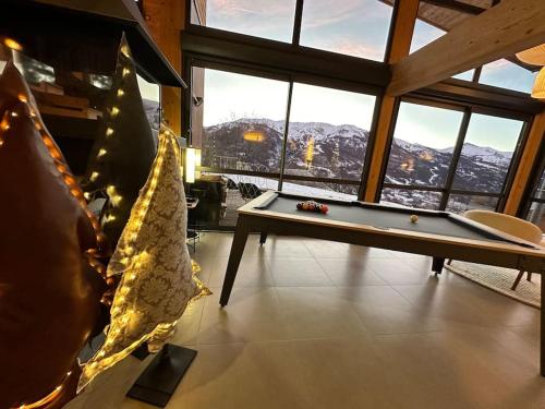 a living room with a pool table in front of windows at Chalet d'architecte avec vue panoramique in Allos