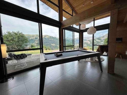 a pool table in a room with a large window at Chalet d'architecte avec vue panoramique in Allos