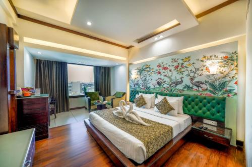 a bedroom with a large bed with a painting on the wall at Hotel Saffron Leaf in Dehradun
