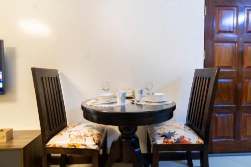 a table with two chairs and a table with glasses on it at Serenity Retreat - 2 Bed Apartment with Pool & Gym in Nairobi