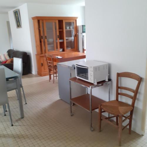 a kitchen with a microwave on a table with chairs at Appartement vue sur l'Eure in Soulaires