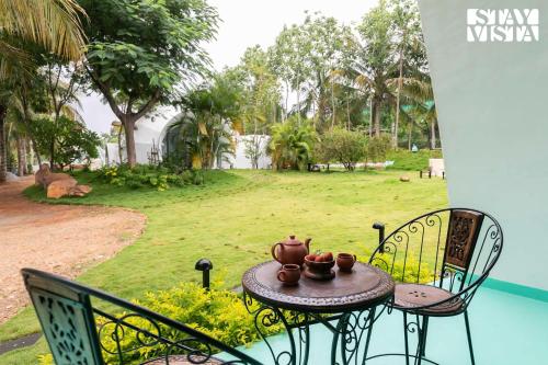 a table and chairs on a porch with a yard at StayVista at Shwaas 4BR Mysore with Private pool and landscape in Mysore