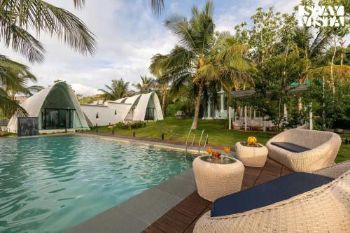 a resort swimming pool with chairs and a tent at StayVista at Shwaas 4BR Mysore with Private pool and landscape in Mysore