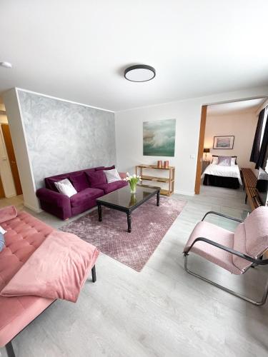 a living room with a purple couch and a table at Gustavelund Apartments in Tuusula