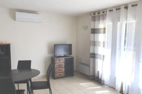 Il comprend un salon doté d'une télévision et d'une table avec des chaises. dans l'établissement Studio 30 m2 proche de Porticcio et d'Ajaccio, à Eccica-Suarella