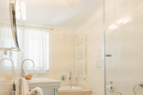 a white bathroom with a shower and a sink at Leonardo Trulli Resort in Locorotondo