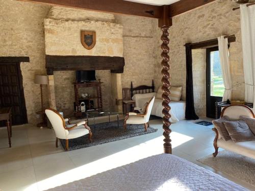 a bedroom with a fireplace and chairs and a bed at Manoir La Barriere - Lot in Le Vigan