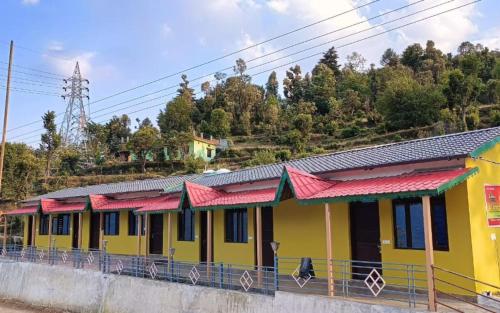 a yellow and red building with red roofs at Om Retreats by StayApart in Gupta Kāshi