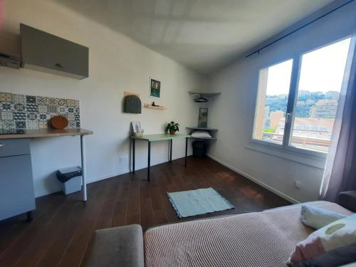 un salon avec un canapé, une table et une fenêtre dans l'établissement La Chambre 3, Climatisée AC, Cuisine privée, Calme, à Nice