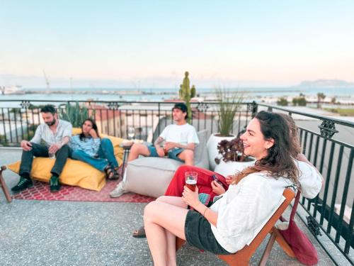 a group of people sitting on a balcony with a glass of wine at Ostello Bello Palermo in Palermo