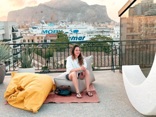a woman sitting on a chair on a balcony at Ostello Bello Palermo in Palermo
