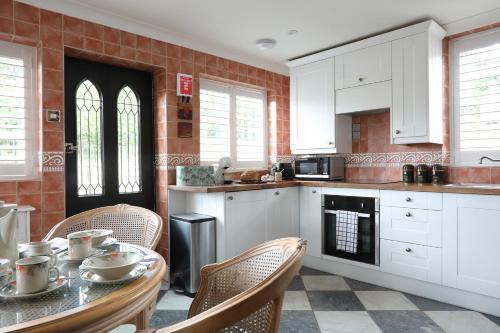 a kitchen with white cabinets and a table with chairs at Palm House - Luxury Wye Valley Country House 2 Bed Apartment - Dog Friendly in Newland