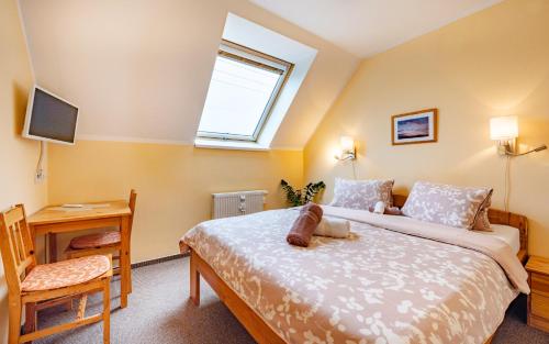 a bedroom with a bed and a desk and a television at Pension Čtyřlístek in Tisá