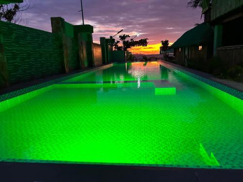 a green swimming pool with a sunset in the background at Oktowaves hotel in Nasugbu