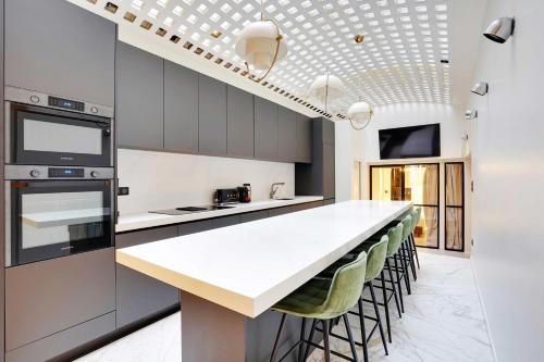 une cuisine avec un comptoir blanc et des tabourets dans l'établissement Bright & cosy apartment Palais Royal, à Paris