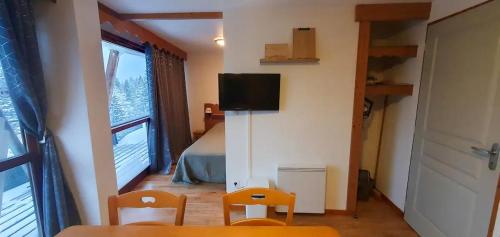 a room with a table and two chairs and a television at Appartement 3 étoiles au pied des pistes avec balcon été in Chamrousse