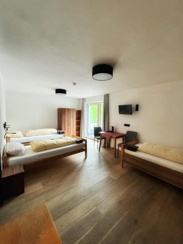 a room with two beds and a desk and a table at SKILL Mountain Lodge - Ski und Bike Hostel im Sommer mit JOKER CARD in Saalbach Hinterglemm