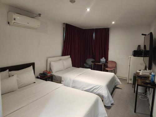 a hotel room with two beds and a window at Pacific7 Hotel in Pyeongtaek