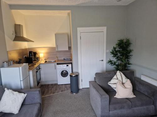 a living room with two couches and a kitchen at Star Apartment in Dumbarton