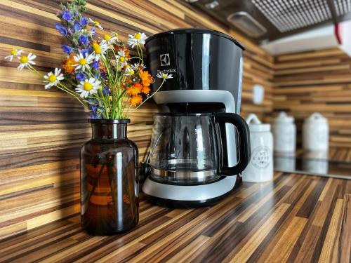 a coffee maker and a vase of flowers on a counter at Penzion Kozí zámek in Horažďovice