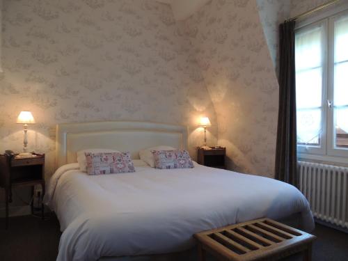 a bedroom with a white bed with two pillows on it at La Villa Bois Joli HOTEL RESTAURANT in Bagnoles de l'Orne