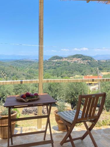 a table with a bowl of fruit and a chair at Dinateli Houses - Live like a local in Corfu in Kastellánoi