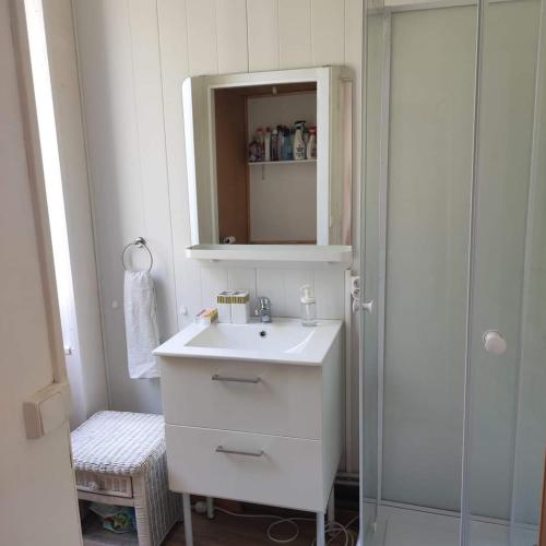 a white bathroom with a sink and a mirror at Les galets in Fouras