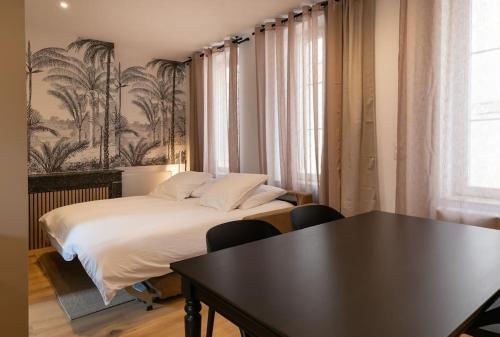 une chambre avec un lit et une table avec des chaises dans l'établissement Cœur de Metz Balnéo - La Suite 3, à Metz
