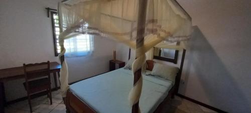 a bedroom with a bed with a canopy and a window at Maison Angèle in Nosy Be