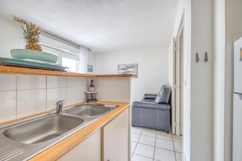 kuchnia ze zlewem i oknem w obiekcie Maison de ville Domaine des sables w mieście Soulac-sur-Mer